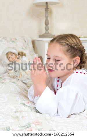 Adorable young girl saying her night time prayers beside her bed