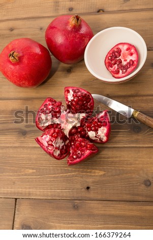 Cut open and closed pomegranates on a wooden table