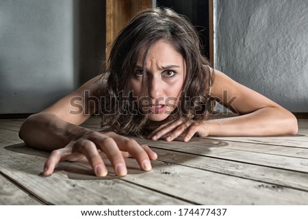 Scared woman crawling on the floor of a derelict house