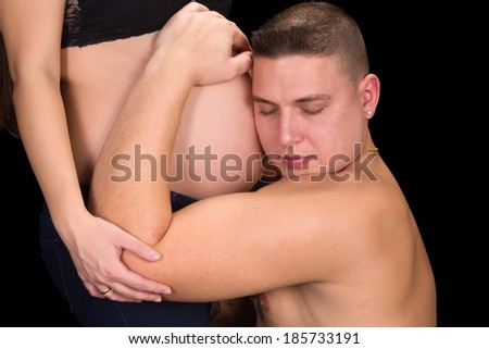Young father holding his wife's pregnant belly in his hands