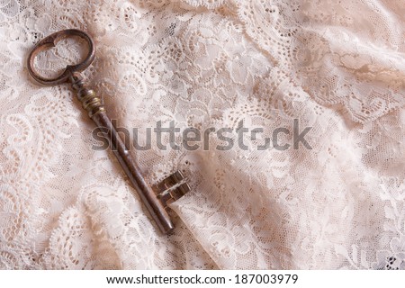 Rusty old key lying on fine antique white lace