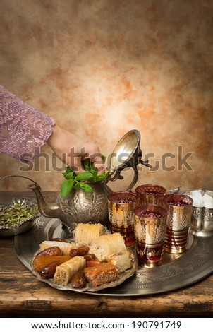 Female hand adding mint leaves on a Moroccan tea tray