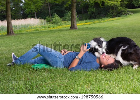 Loving border collie dog licking his boss in the park