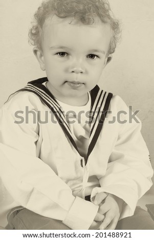 Cute little victorian toddler boy dressed in vintage sailor costume
