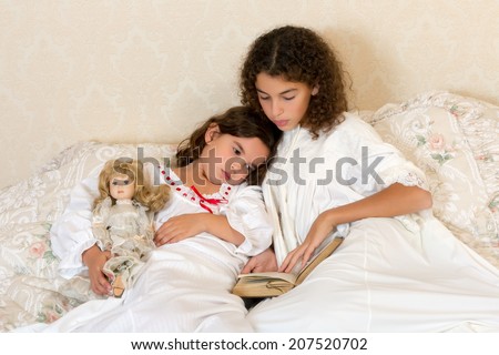 Vintage girl in bed reading a bedtime story to her little sister