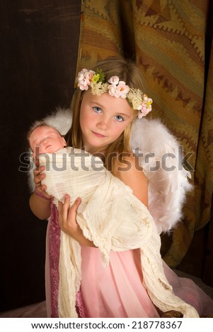 Pink little girl playing an angel in a Christmas nativity scene with a doll