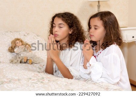 Adorable victorian girls kneeling in their vintage bedroom and praying