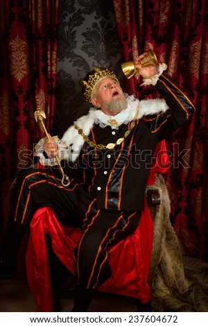 Old funny king getting drunk holding a golden goblet