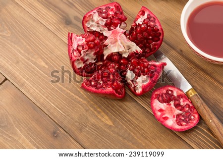 Cut open pomegranate and bowl of juice on a wooden table