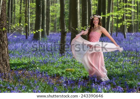 Innocent young woman with pink fairy dress in a springtime bluebells forest