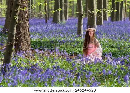 Innocent young woman with pink fairy dress in a springtime bluebells forest
