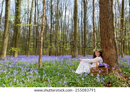 Victorian woman in white dress in a springtime bluebells forest