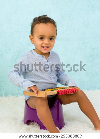 Potty training of a cute African toddler boy playing with an abacus