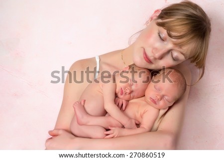 Beautiful young mother holding her ten days old newborn twin baby girls