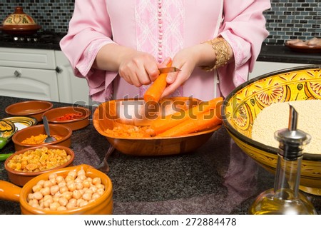 Hands of an immigrant woman in a modern European kitchen adding carrots to a traditional Moroccan tajine during Ramadan nights