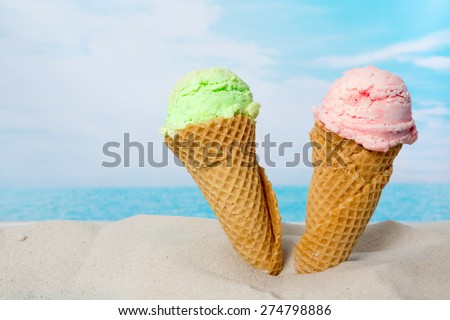 Funny image of two ice cream cones in the beach sand