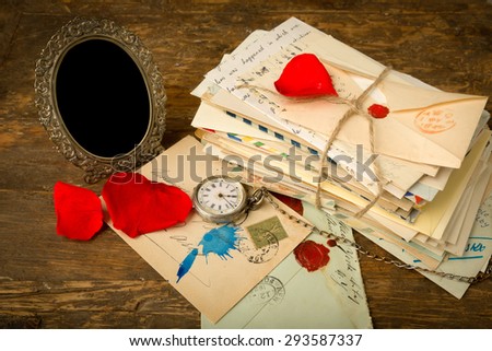 Empty antique picture frame and a pile of old letters on a wooden table