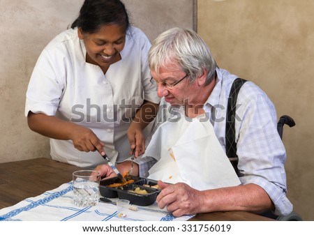 Nurse in old people\'s home trying to make a patient eat his dinner