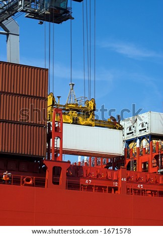 Detail of one container being loaded into a cargo ship (all brand names and logos have been removed)