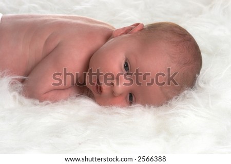 Very young baby lying on a pure white carpet