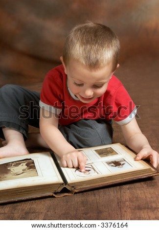 Young boy browsing an antique family album (the faces on the photos in the album cannot be recognized)