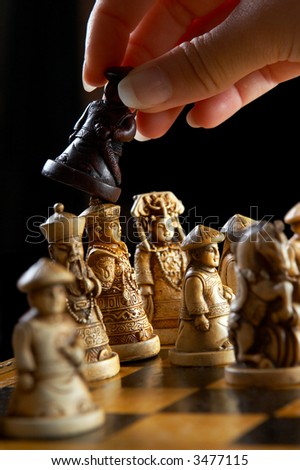 Hand playing chess with an antique chess set, view on the moment of checkmate