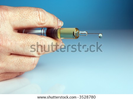 Hand holding a small flu vaccination syringe