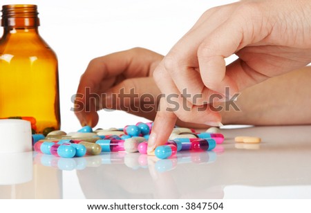 Manicured hand selecting pills, capsules and tablets