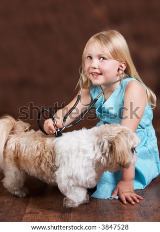 Little blond girl playing doctor with her Shih-tzu dog