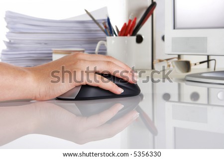 Female hand on a computer mouse, reflective surface, and office environment