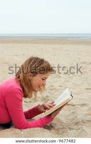 Young woman reading a funny book on the beach