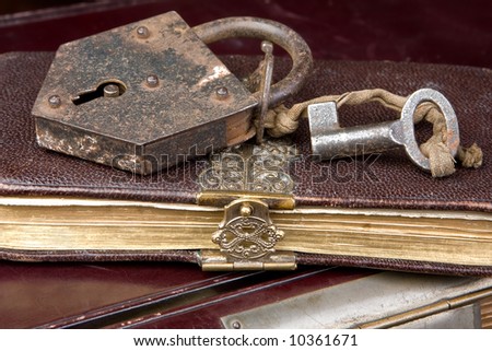 Padlock and key on very old locked books