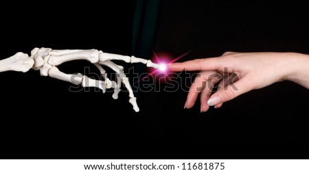 Hands of a woman touching the hand of a skeleton