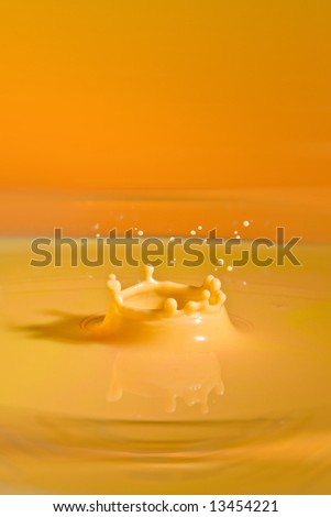 Splashing droplet falling into a pool of yellow colored milk