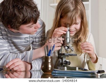 stock photo : Two teenagers helping each other with a microscope