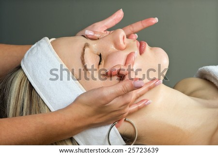 Hands giving a young woman a facial massage