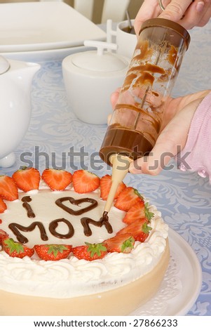 Hands writing Mommy on a mother\'s day cake