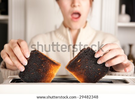 Hands of a woman taking burnt toast out of a toaster