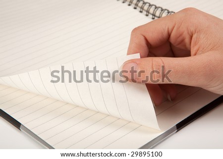 Female hand turning a page of an empty notebook