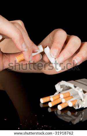 Female hand breaking a cigarette to stop smoking