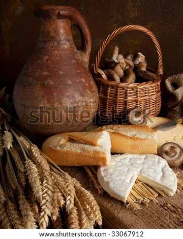 Rustic country still life of bread, cheese and an old wine jar