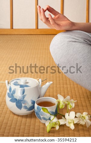 Meditating woman on japanese tatami mat with green tea and orchids