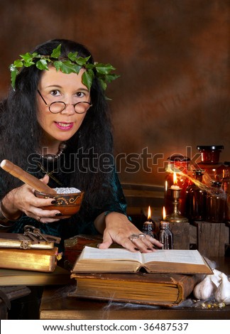 Halloween witch preparing herbs using old books for spells and recipes