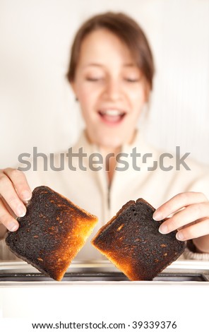 Surprised woman taking burnt toast out of a toaster