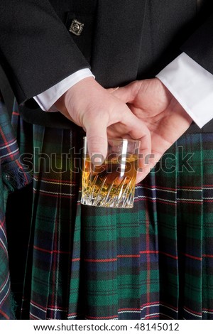 scotsman in kilt. stock photo : Scotsman holding his glass of whisky behind is kilt