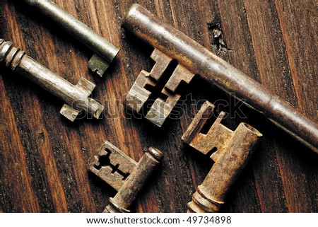 Grunge image of antique rusty keys on a weathered wooden background