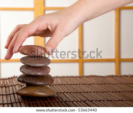 Hand stacking zen stones in a japanese interior with shoji sliding windows