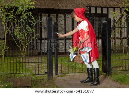Little red riding hood opening the gate the her grandmother\'s cottage