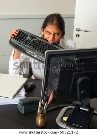 Young frustrated and angry employee chewing on his keyboard