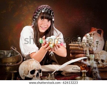 Young halloween witch holding a handful of trick or treat candy (the book is 300 years old, no copyright problems)